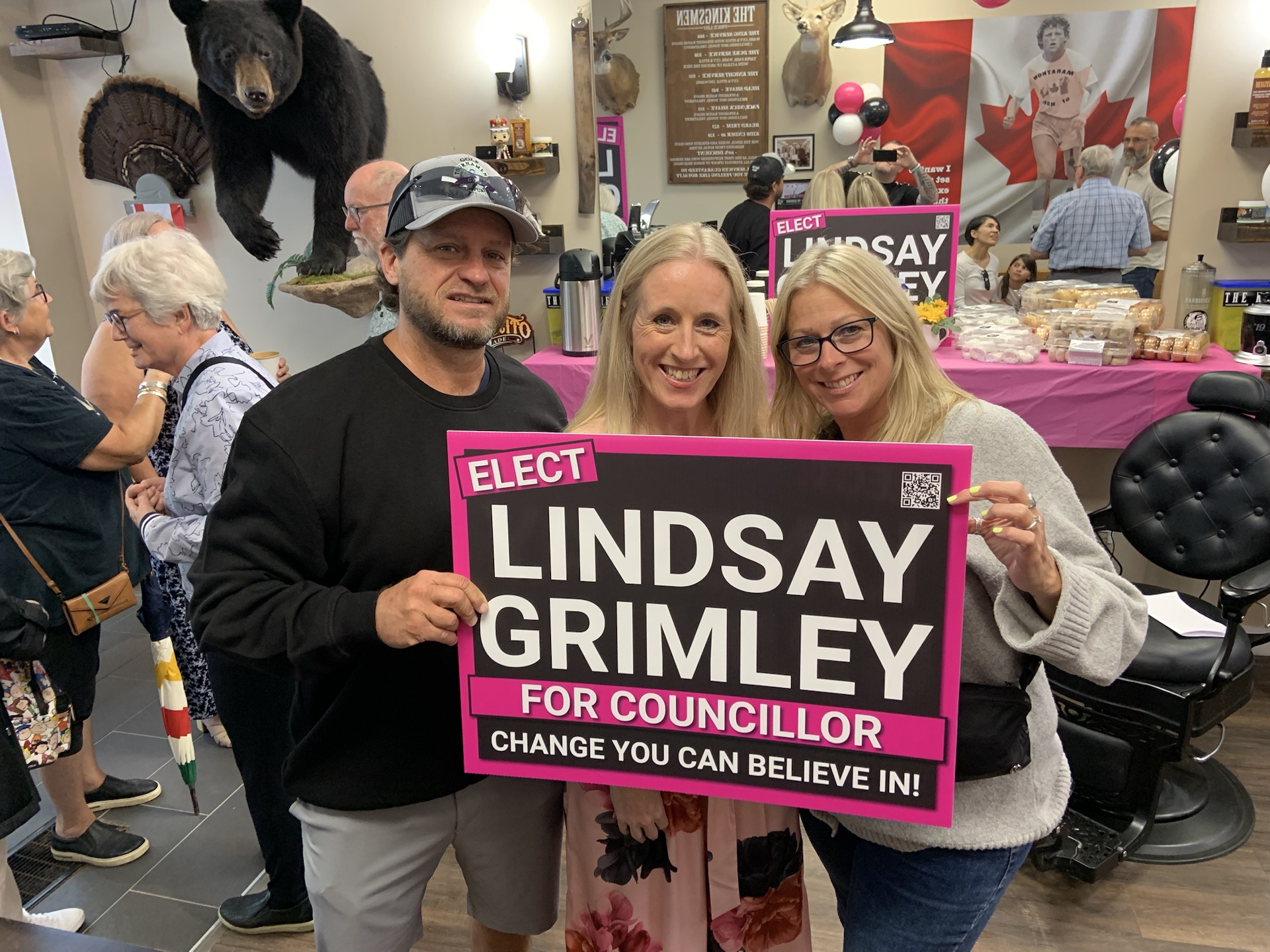 Lindsay Grimley with supporters holding an Elect Lindsay Grimley for Councillor sign at The Kingsmen, with guests and refreshments in the background