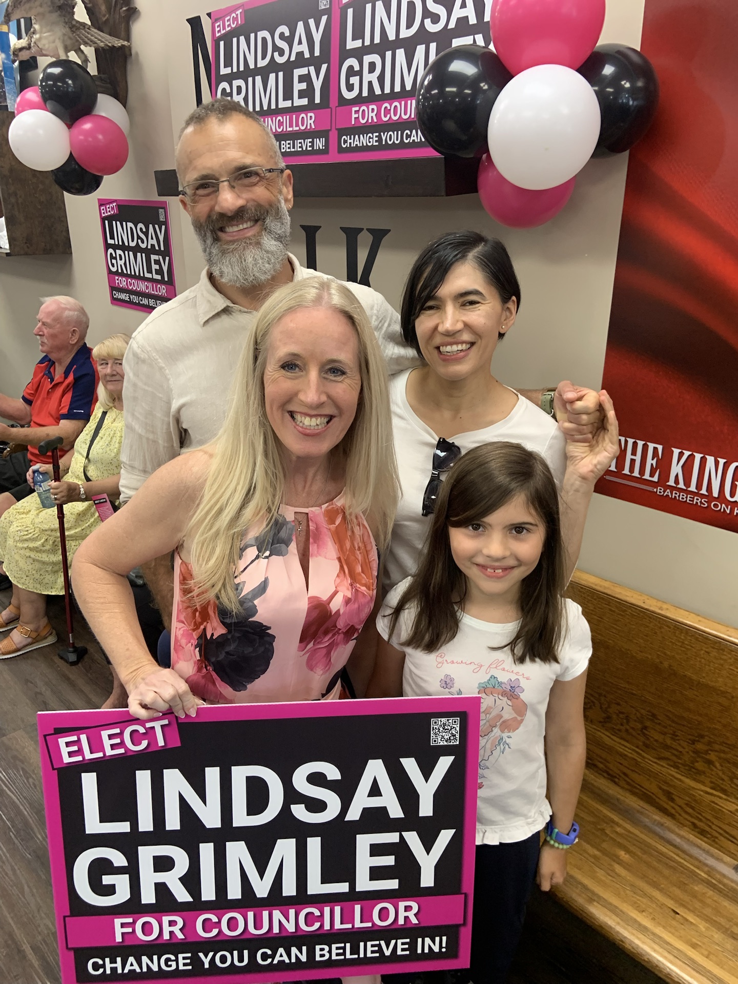 Lindsay Grimley holding a campaign sign with a child and guests at the launch party
